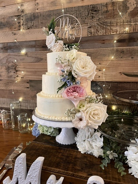 Three-tiered white buttercream wedding cake with cascading roses and Mr & Mrs topper