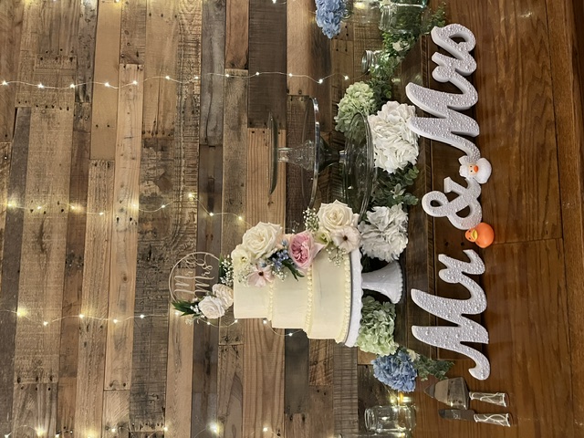 Full vertical display of wedding cake on rustic wood table with Mr & Mrs sign and rubber ducks