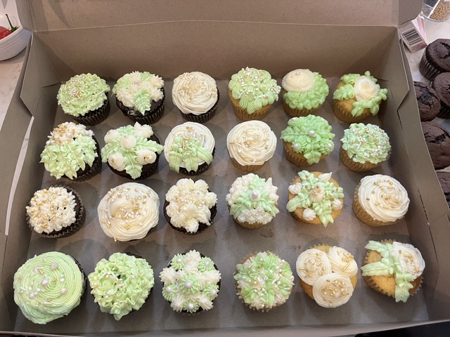 Box of two dozen baby shower cupcakes with custom green and white floral buttercream piping and pearls